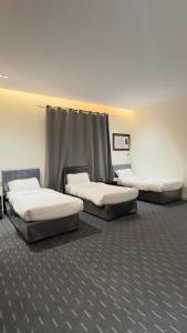 three beds are lined up in a room at Madain Al Baraka Suites أجنحة مدائن البركة in Medina