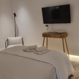 a bedroom with a bed and a table with a tv at Oro suites budget in Mikonos