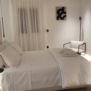 a bedroom with a white bed and a chair at Oro suites budget in Mikonos +1 photo