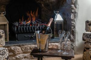 a bucket of champagne and two wine glasses in front of a fireplace at Storehouse Cottage in Penrhyn Bay