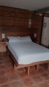 ein Bett in einem Schlafzimmer mit einem hölzernen Kopfteil in der Unterkunft Andivi in Arroyo Cruz