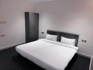 a bedroom with a large bed with white sheets and pillows at Madain Al Baraka Suites أجنحة مدائن البركة in Medina