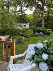 due sedie bianche e un vaso di fiori su un ponte di Mobil home tout confort a Saint-Chéron
