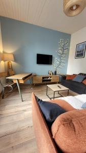 a living room with a couch and a flat screen tv at Maison élégante entre Ré et Marais in Marans