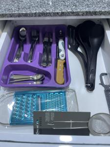 un plateau en plastique violet avec des ustensiles dans un tiroir dans l'établissement Bayt Hassan S18 - Fabulous Roof top 1 bedroom apartment, à Hurghada