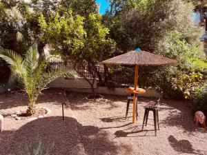 an umbrella and a chair and a table and stool at Garden villa two-bedroom suite in Vari