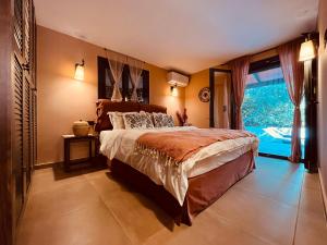 a bedroom with a large bed and a large window at Garden villa two-bedroom suite in Vari