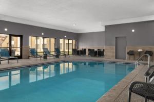 Una piscina en una habitación de hotel con sillas y mesas. en Holiday Inn Coralville - Iowa City by IHG, en Coralville