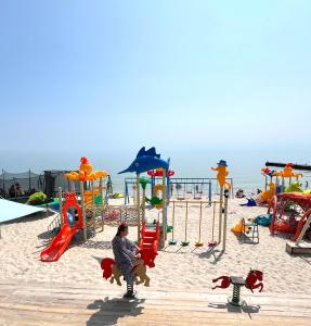 a woman sitting on a playground at the beach at VEM Apartment Калипсо in Odesa