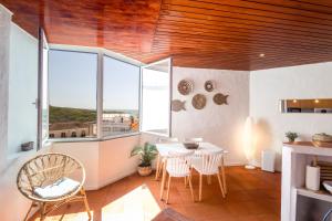 a dining room with a table and chairs and windows at Muito acolhedor com vista de mar in Colares