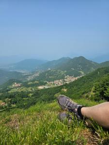 uma pessoa sentada no topo de uma colina gramada com o pé em Puravida 4seasons NATURE HIDEAWAY between lake Garda and Idro em Arveaco