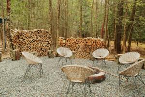 un groupe de chaises assises devant un tas de bûches dans l'établissement Riverfront Cottage with Sauna & Hot Tub, à Liberty