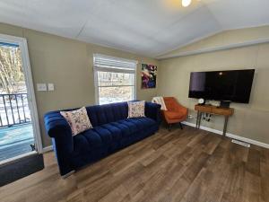 un salon avec un canapé bleu et une télévision à écran plat dans l'établissement Riverfront Cottage with Sauna & Hot Tub, à Liberty