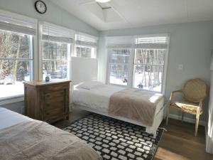 une chambre avec un lit, une chaise et des fenêtres dans l'établissement Riverfront Cottage with Sauna & Hot Tub, à Liberty