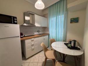 a kitchen with a table and a white refrigerator at Leonidas Apartments & Suites 2 in Mola Kalyva