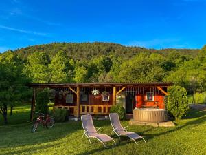 a house with two chairs and a fire pit in the grass at Home La Sierra with WHIRLPOOL BATH for two in Korenica