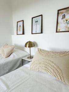 a white bedroom with two beds and a lamp at Casinha do Amor in Guia