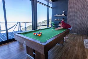 un jeune garçon jouant au billard dans une salle avec billard dans l'établissement Secluded Dream Home with Hot Tub and Full Gym on 20 Acres, à Palomar Mountain