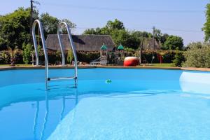 an empty swimming pool with blue water at Les Mini-Chaumières in Saint-Martin-Saint-Firmin