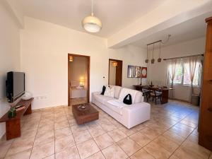 a living room with a white couch and a table at Nostos Apartment Galatas in Galatas