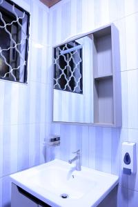 a white bathroom with a sink and a mirror at AG Home Studio - Kampala in Kampala