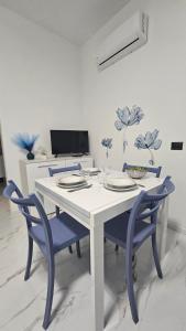 una sala da pranzo con un tavolo bianco e sedie blu di Violet Luni Home a Marinella di Sarzana