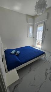 una camera da letto con un letto blu con una finestra di Violet Luni Home a Marinella di Sarzana