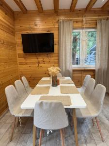 a dining room with a white table and chairs at Serska Chatyna in Serwy