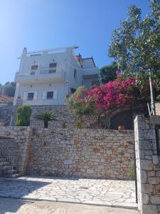 een gebouw achter een stenen muur met roze bloemen bij Kamares View in Ayeranós +11 foto's