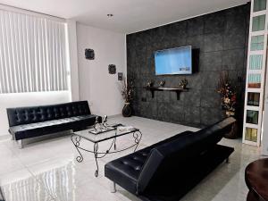 a living room with a black couch and a table at Santa Cecilia Casa elegante acogedora y amplia in Tehuacán