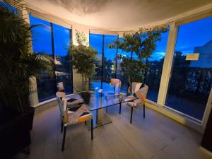 a glass table and chairs in a room with windows at Panoramic Pondview Penthouse in London