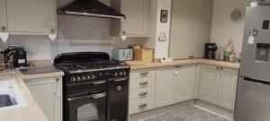 a kitchen with a black stove and white cabinets at Tyrstafell in Llangendeirne