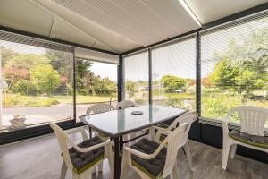 een eetkamer met een tafel, stoelen en ramen bij Maison familiale proche mer - Etables-sur-Mer in Binic