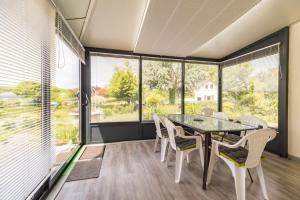 een eetkamer met een tafel en stoelen en grote ramen bij Maison familiale proche mer - Etables-sur-Mer in Binic