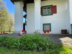 Una casa blanca con flores rojas delante de ella. en Tôlluste Villa, en Tõlluste