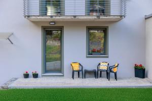 three chairs and a table in front of a house at Revo Apartments - Campelli in Albosaggia