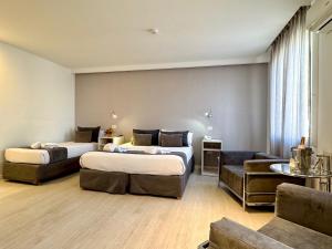 a hotel room with two beds and a couch at Hotel Majestic Rosario in Rosario +21 photos