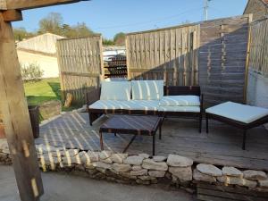 a patio with a couch and a bench on a deck at Papillon de la peroterie in Mauzé-sur-le-Mignon