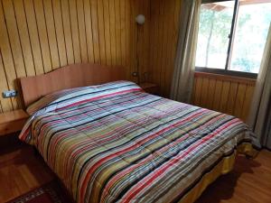 a bedroom with a bed with a colorful blanket on it at Cabaña para 6 personas camino a Termas de Chillán in Pinto