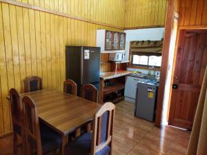 a kitchen with a wooden table and a refrigerator at Cabaña para 6 personas camino a Termas de Chillán in Pinto