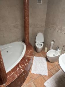 a bathroom with a tub and a toilet and a sink at Chez Bouchra in Mansouria