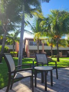 three chairs and a table in a park with palm trees at Eagle Beach luxury house, walking distance to the beach in Palm-Eagle Beach