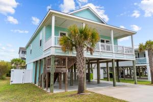 una casa con una palmera delante en Beachside Charm Pool Spa & 3-Min Walk to Shore, en Oak Island