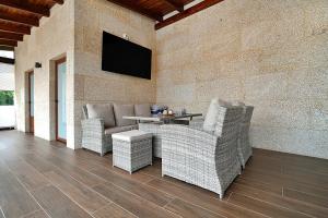 eine Terrasse mit Korbstühlen und einem TV an der Wand in der Unterkunft GALIHOST - Casa Valboa in Meis