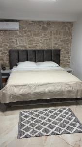 a bedroom with a large bed with a stone wall at House Sela vrata in Bibinje