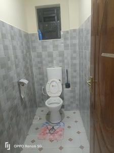 a bathroom with a toilet in a tiled room at KISERIAN Stay Home Accomodation in Nairobi