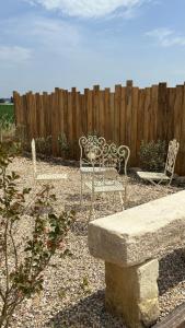 a patio with two chairs and a table and a fence at Cottage RG in Lamothe-Landerron