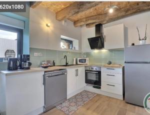 a kitchen with white cabinets and a refrigerator at Entre terre et mer in Val Couesnon