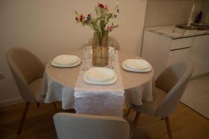 a table with chairs and a vase with flowers on it at Apartman Superior Centar in Trebinje