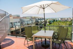 una mesa y sillas con una sombrilla en el balcón en Ático Premium con Azotea, Pádel y Piscina, en Sant Jordi (San Jorge)